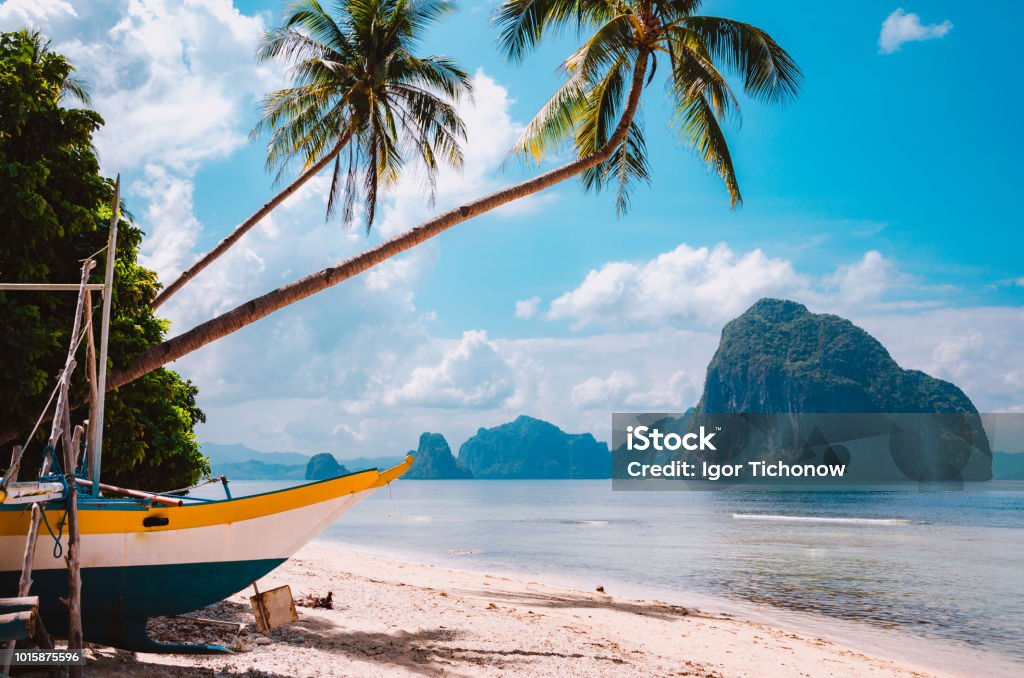 Banca boat on shore under palm trees.Tropical island scenic landscape. El-Nido, Palawan Banca boat on shore under palm trees.Tropical island scenic landscape. El-Nido, Palawan, Philippines, Southeast Asia Philippines Stock Photo