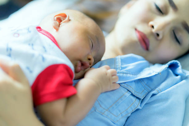 The Newborn baby sleeping on mother's chest. Co-sleeping mother and baby child. Young beautiful mother recovering after childbirth. stock photo
