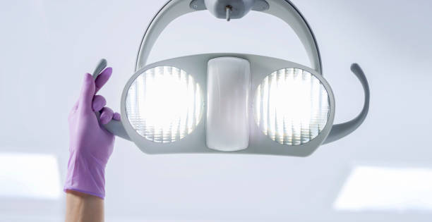 Female hand wearing glove moving dental light Female hand in violet glove moving dental light. dental light stock pictures, royalty-free photos & images