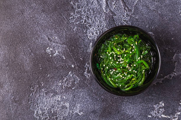 салат из морских водорослей чука на черном фоне - wakame seaweed salad seaweed salad стоковые фото и изображения