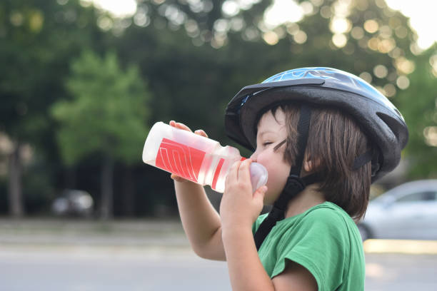 istock Little cyclist with a helmet drinks water 1015895592