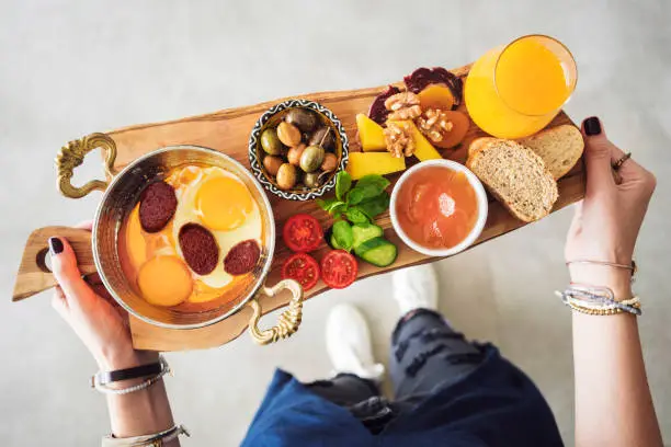 Photo of Woman carrying delicious traditional turkish breakfast on cutting board