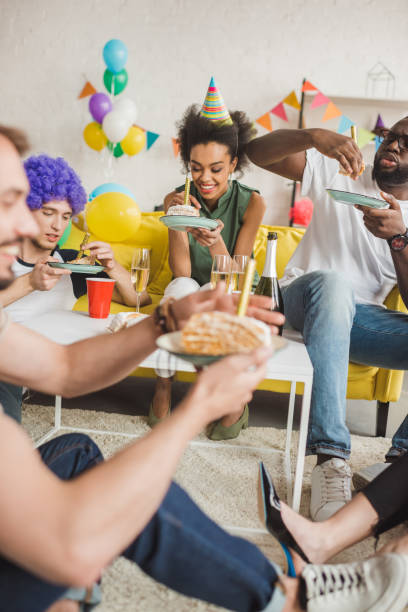 istock Partying diverse people eating birthday cake and holding drinks 1015928120