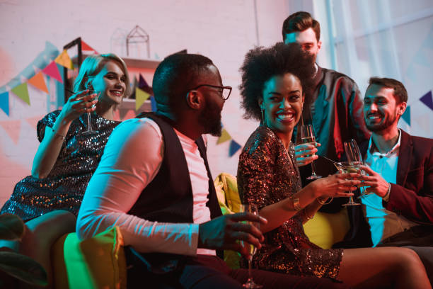 istock Young multiracial people celebrating with drinks in cozy room 1015928372