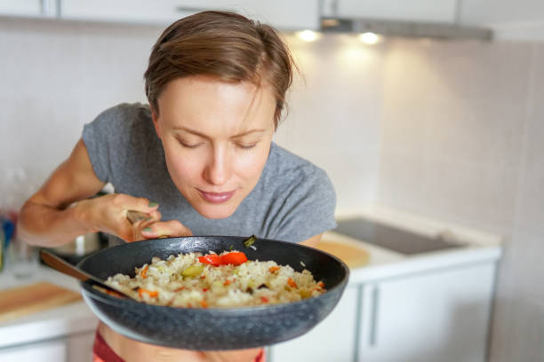 donna che tiene padella con riso e verdure - flavored rice foto e immagini stock