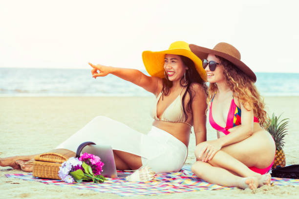 istock Happy women sitting on sand beach in summer. 1015933572