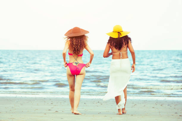 istock Happy women go sunbathing at sand beach in summer. 1015933582