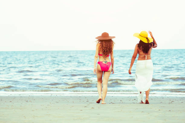 istock Happy women go sunbathing at sand beach in summer. 1015933664