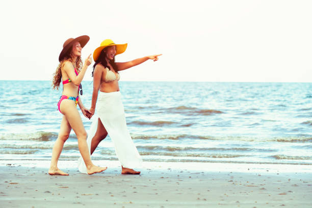 istock Happy women go sunbathing at sand beach in summer. 1015933686
