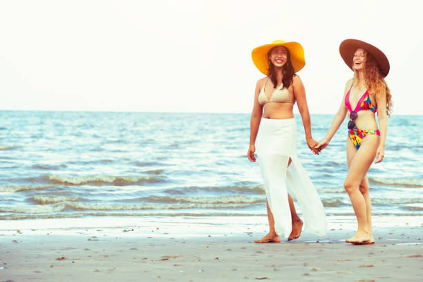 istock Happy women go sunbathing at sand beach in summer. 1015933688