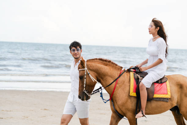 istock Young couple goes horse riding on tropical beach. 1015934202