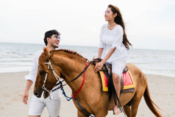 istock Young couple goes horse riding on tropical beach. 1015934218