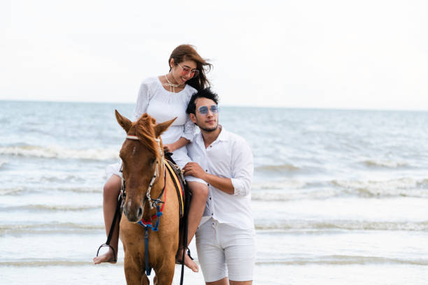 istock Young couple goes horse riding on tropical beach. 1015934246