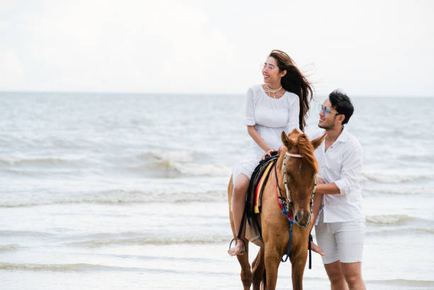 istock Young couple goes horse riding on tropical beach. 1015934254