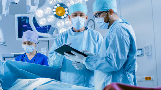 istock Professional Surgeons and Assistants Talk and Use Digital Tablet Computer During Surgery. They Work in the Modern Hospital Operating Room. 1015934852