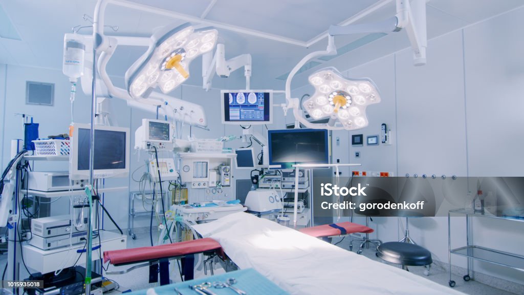 Establishing Shot of Technologically Advanced Operating Room with No People, Ready for Surgery. Real Modern Operating Theater With Working equipment,  Lights and Computers Ready for Surgeons and a Patients. Operating Room Stock Photo