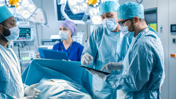 istock Professional Surgeons and Assistants Talk and Use Digital Tablet Computer During Surgery. They Work in the Modern Hospital Operating Room. 1015935028