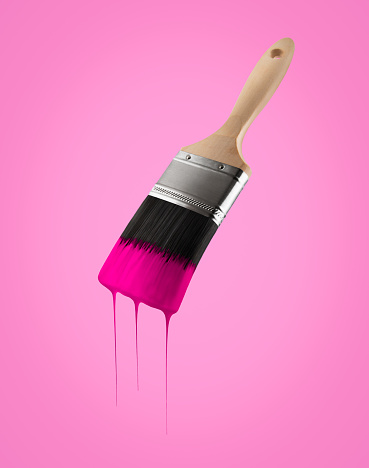 Paintbrush loaded with pink color dripping off the bristles- Isolated on pink background.