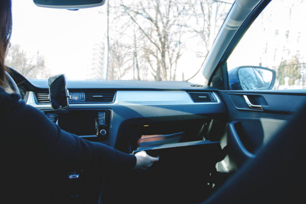 istock woman driving, opens the glove box to store documents 1015939298