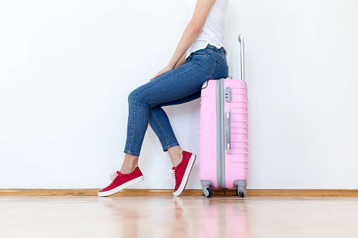 Young woman stands beside suitcase