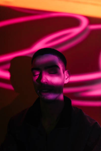 Young man illuminated by neon lights Young man illuminated by neon lights fluorescent photos stock pictures, royalty-free photos & images