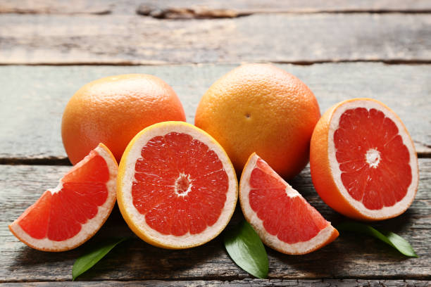 istock Ripe grapefruits with green leafs on grey wooden table 1015949948
