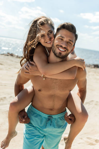 istock happy man piggybacking his girlfriend on beach 1015954226