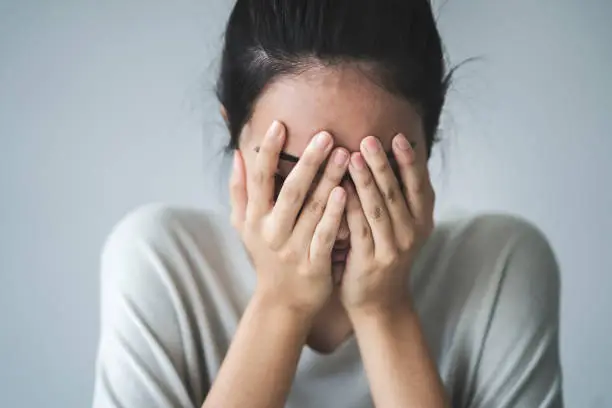 Young girl covering her face with her hands