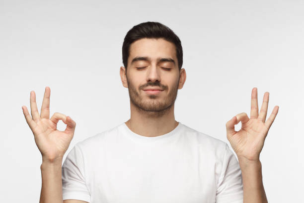 istock Concentrated relaxed man standing with closed eyes, having relaxation while meditating, trying to find balance and harmony. Yoga and meditation concept 1015970272