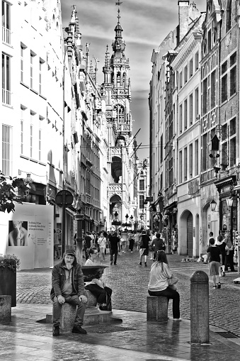 Tourists in Brussels down a side street near the Grand Place, they are sitting and walking in front of the buildings.