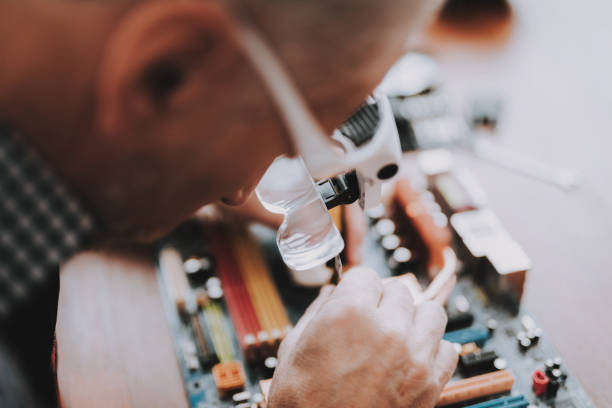 z bliska. old man naprawa płyty głównej z komputera. - male magnifying glass caucasian technician zdjęcia i obrazy z banku zdjęć