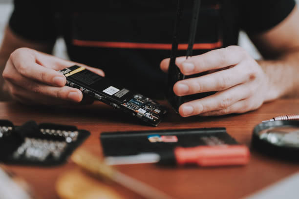 istock Close up Young Man Repairing Mobile Phone at Table 1015975894