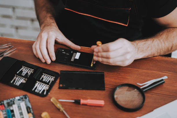istock Close up Young Man Repairing Mobile Phone at Table 1015975962