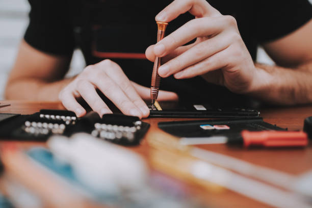 istock Close up Young Man Repairing Mobile Phone at Table 1015976076