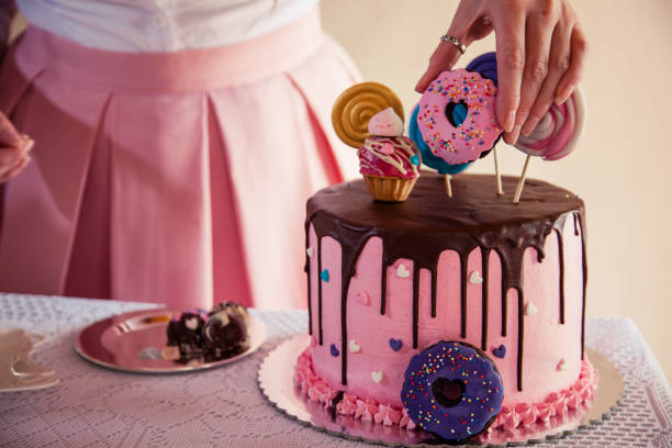 Colorful and delicious cake Close-up shot of a woman decorating a large cake with variety of small colorful cakes. decorating a cake photos stock pictures, royalty-free photos & images