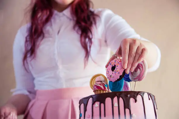 Low angle shot of a woman decorating a cake for children's birthday.