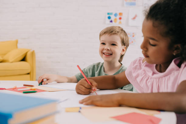 istock selective focus of multicultural preschoolers at table with papers and pencils in classroom 1015998896