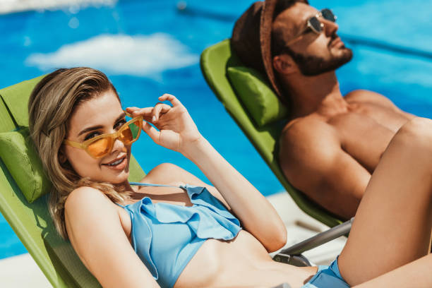 istock young couple in sunglasses relaxing on sunbeds at poolside 1016006338