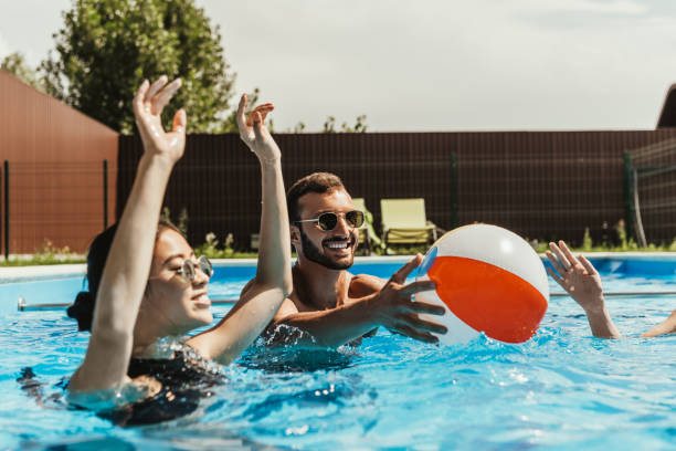 istock multiethnic friends playing with beach ball in swimming pool 1016006880