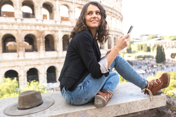 femme souriante, assis en face du colisée - international landmark italy amphitheater ancient photos et images de collection