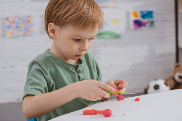 istock focused boy with colorful plasticine sculpturing figure at table in room 1016014496