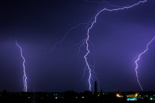 istock Lightning storm over city in purple light 1016018058