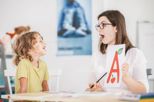 terapeuta da fala a trabalhar com uma criança em uma pronúncia correta usando um adereço com uma letra 'a' imagem. - behavioral problems - fotografias e filmes do acervo