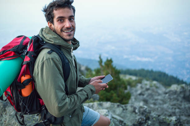istock Cheerful man texting on his phone while resting on the mountain top 1016032446