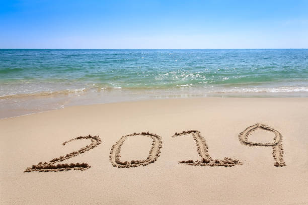 istock Year 2019 written at the sand beach with sea wave water 1016035096