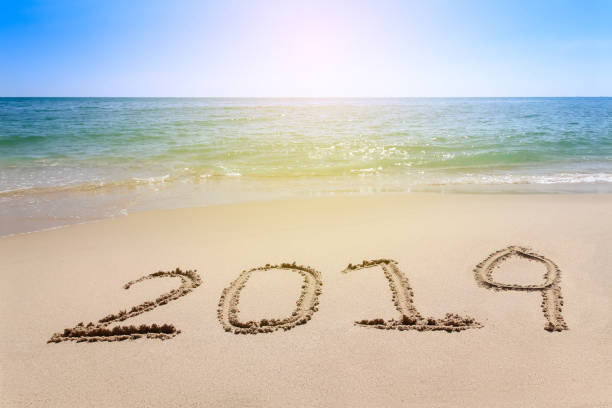 istock Year 2019 written at the sand beach with sea wave water 1016035102