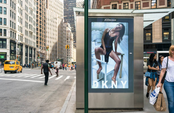 DKNY Advertising on Manhattan Street New York City, USA - Pedestrians and traffic passing a bus stop with an advertisement for the fashion brand Donna Karen New York (DKNY). retail digital signage stock pictures, royalty-free photos & images