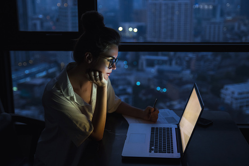 Mujer está trabajando con el portátil en casa durante la noche. photo