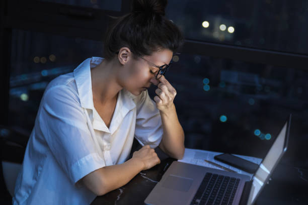 Woman is working with laptop at home during night.