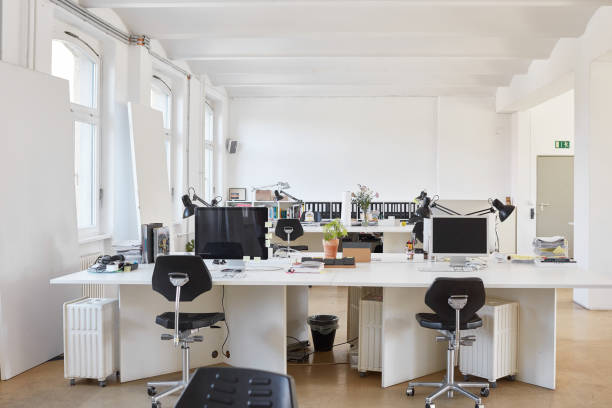 Chairs arranged at desk in office Empty chairs arranged by table in office. Computers are on desk. Interior of modern workplace. workplace absence stock pictures, royalty-free photos & images